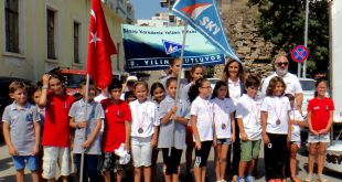 Bayraklarla açılış töreninde sıralanmış spor kıyafetli çocuklar