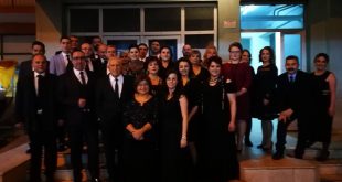 Siyah kıyafetli koro üyelerinin sahne önünde toplu fotoğrafı