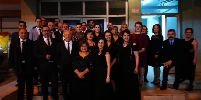 Siyah kıyafetli koro üyelerinin sahne önünde toplu fotoğrafı