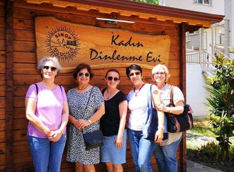 Kadın Dinlenme Evi tabelası önünde poz veren kadınlar grubu