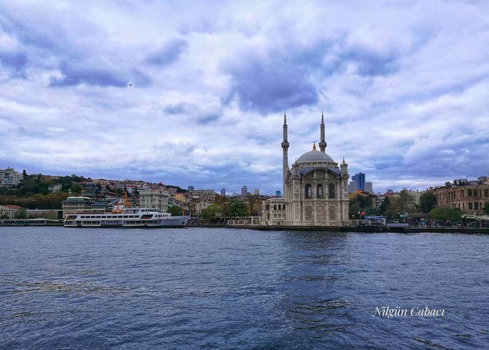 Ortaköy Camii önünden geçen bir tekne ve boğaz manzarası.