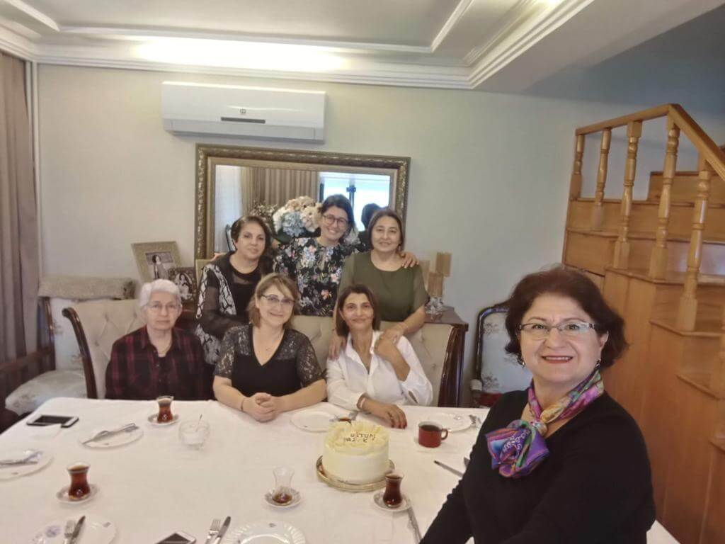 Doğum günü pastası olan bir masada bir araya gelen kadınlar.