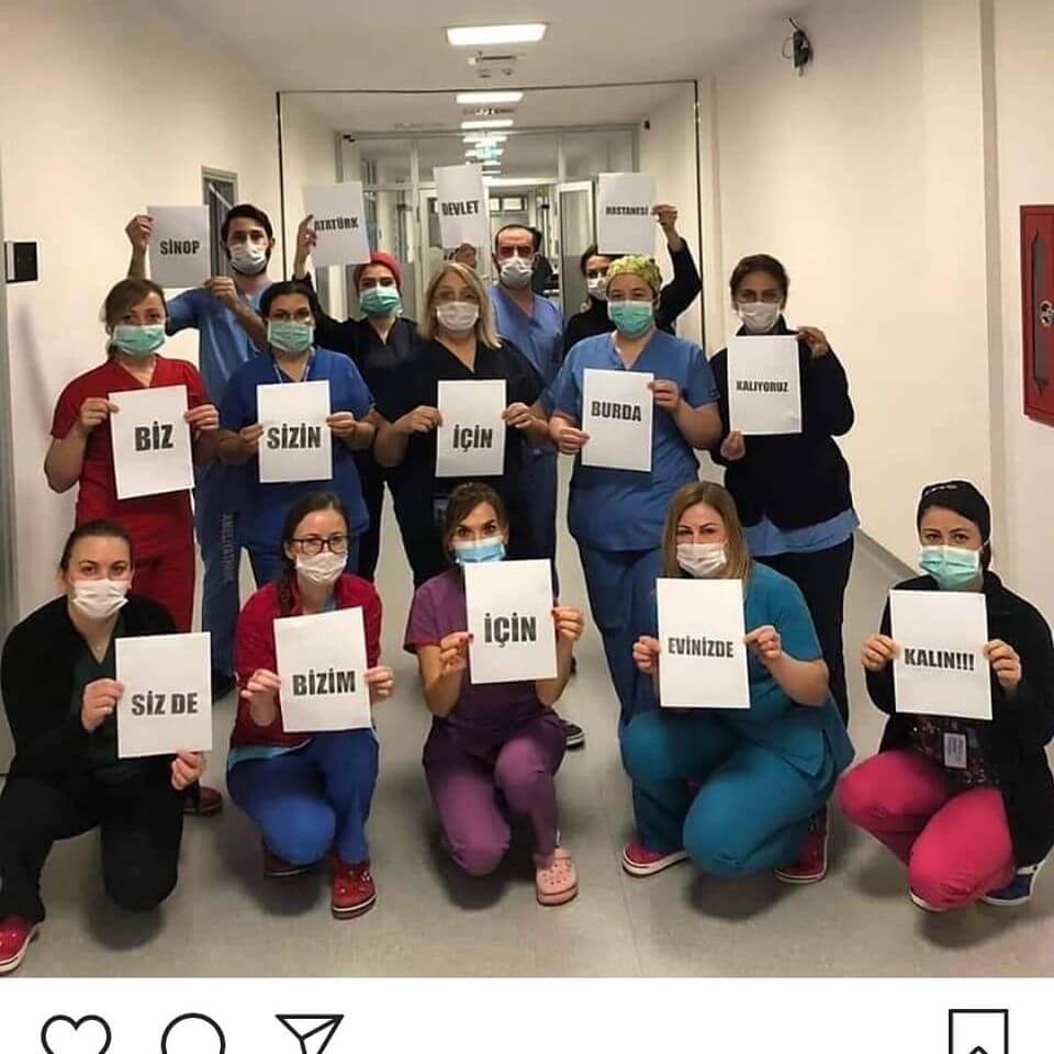 Hastane koridorunda elinde destek mesajları yazılı kağıtlar tutan sağlık çalışanları.