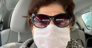Arabada oturan, maske takmış bir kadın.