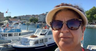 Kadın Sinop limanında tekneler önünde şapka ve güneş gözlüğüyle selfi çekiyor