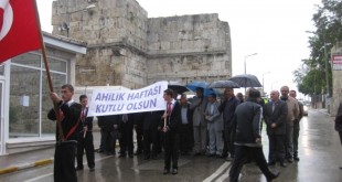 Yağmurlu havada bayrak ve Ahilik Haftası pankartıyla yürüyen erkek grubu
