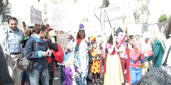 Sokakta pankartlar taşıyan kostümlü çocuklar ve yetişkinler bir arada