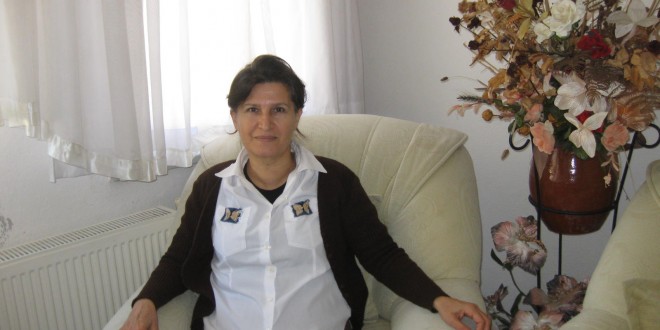 Evde beyaz koltukta oturan kadın ve yanında kuru çiçek aranjmanı