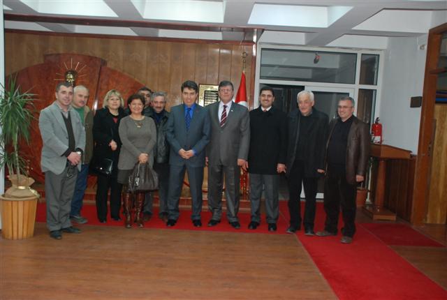 Kırmızı halılı resmi bir salonda toplu hatıra için poz veren grup